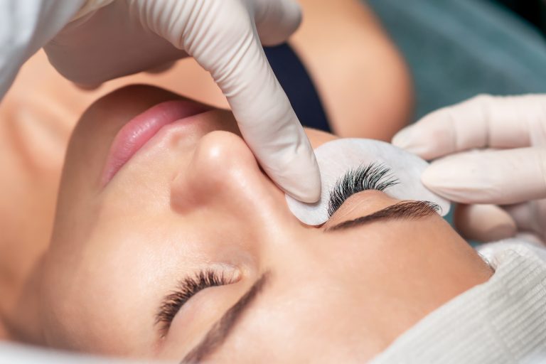 Young woman receiving extending the eyelashes in a beauty salon, close up, eyelash extension procedure.